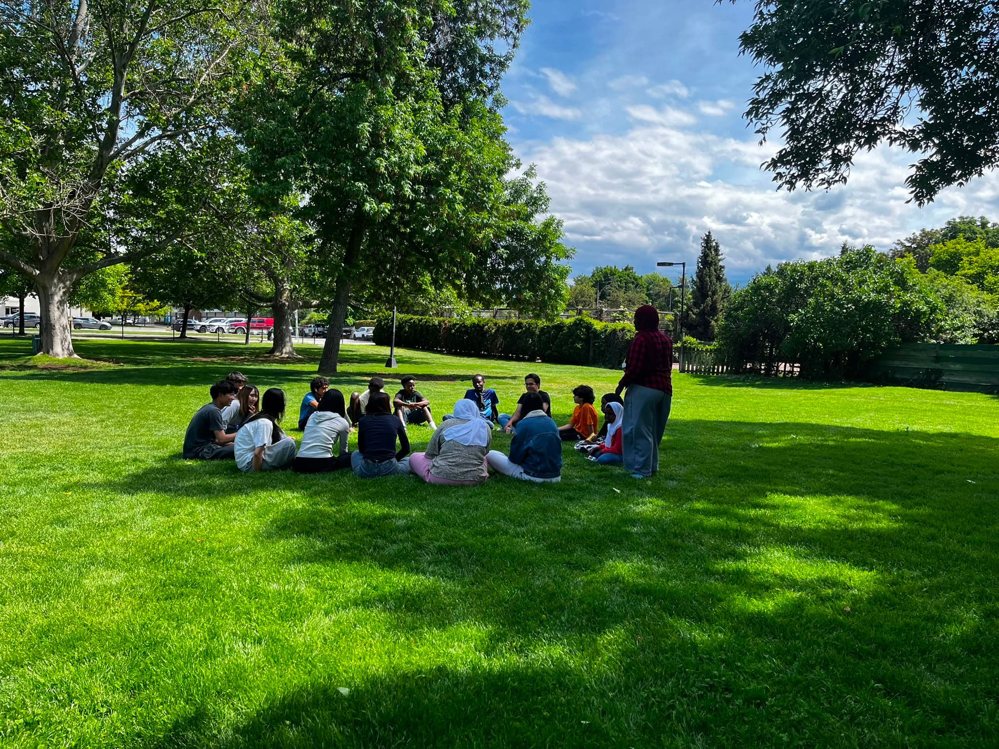 Children sitting in a circle on the grass for an outdoor class